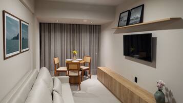 Una sala de estar moderna con sofá, mesa de comedor, sillas, televisor y una consola con un jarrón.