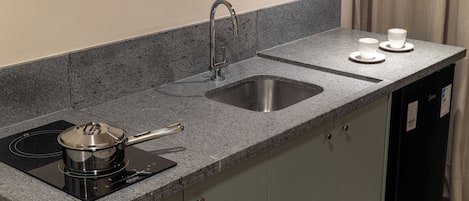 Cozinha com bancada de granito, pia de aço inoxidável e fogão por indução preto.