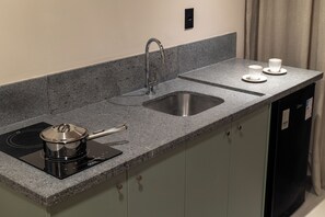 A kitchen with a granite countertop, stainless steel sink, and a black induction cooktop.