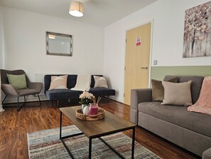 Un salon comprenant un canapé, un fauteuil et une table basse agrémentée d’un objet décoratif.