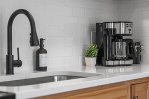 Eine Küche mit einem modernen Wasserhahn, einer Kaffeemaschine und einer Flasche Geschirrspülmittel.