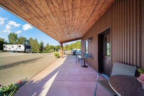 A covered outdoor area with a concrete patio, a table and chairs, and a view of a trailer park in the background.