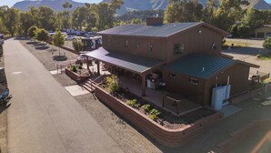 A building with a covered patio area, a fenced parking lot, and a mountainous backdrop.