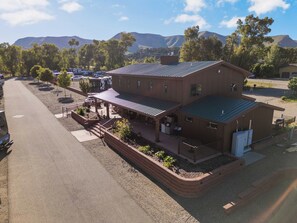 A building with a covered patio area, a fenced parking lot, and a mountainous backdrop.