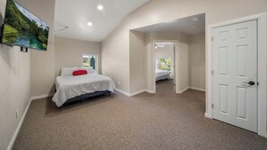 A bedroom with a bed, a door, and a view of a garden through a window.