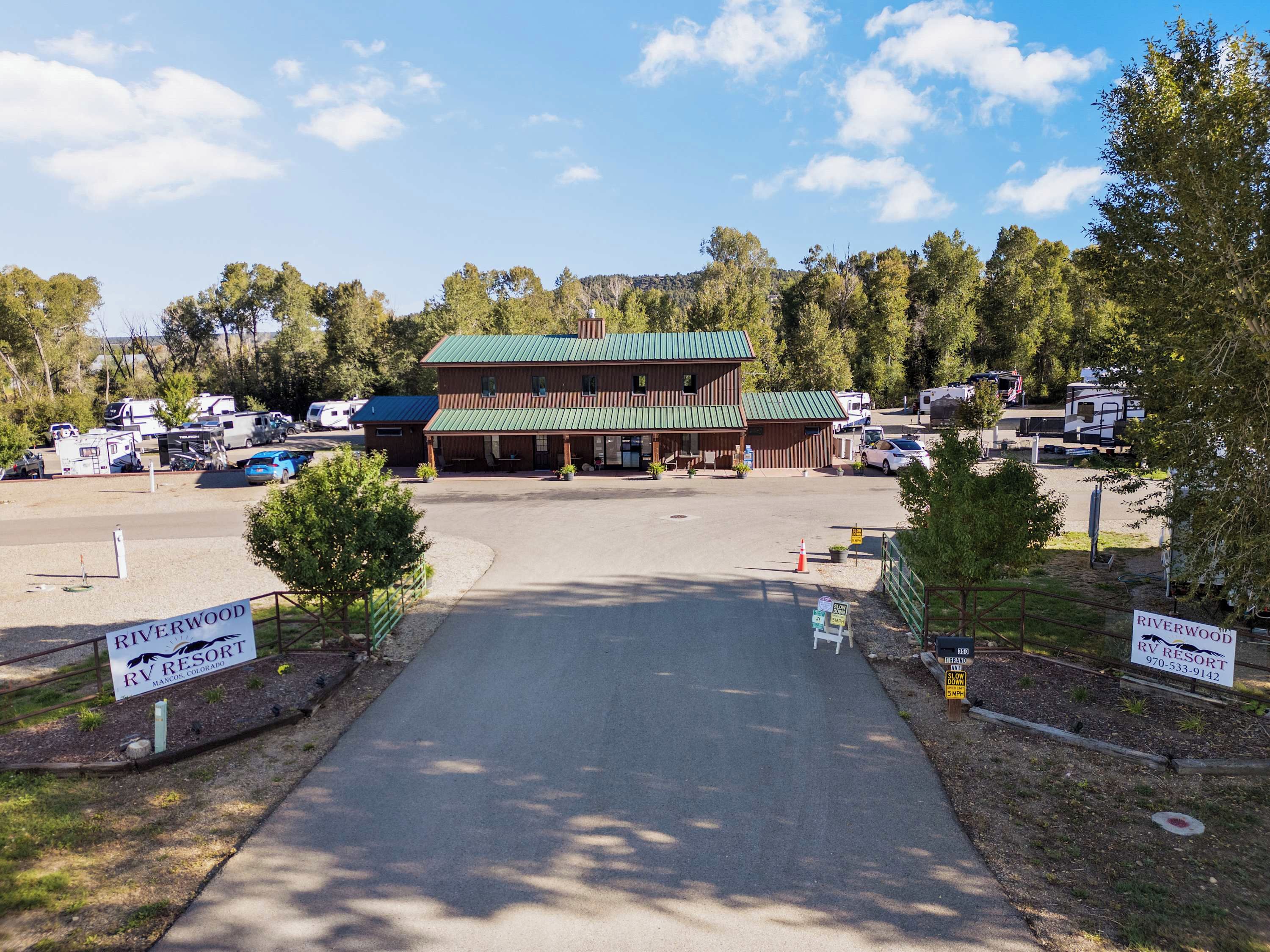 Un camping con vehículos recreativos estacionados frente a un alojamiento con techo verde.