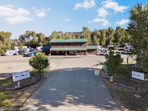 A campground with RVs parked in front of a lodge with a green roof.