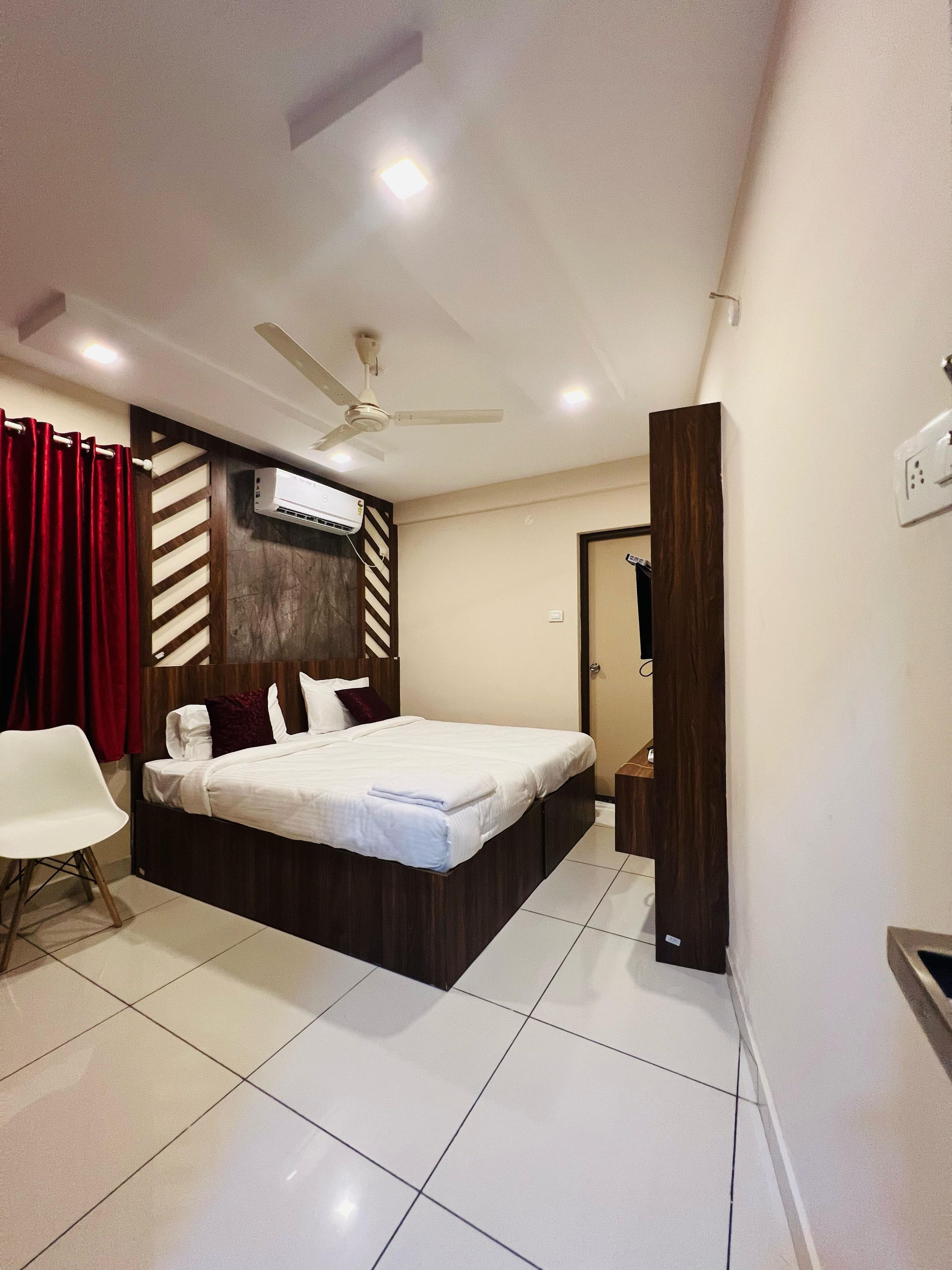A bedroom with a bed, a chair, a ceiling fan, and an air conditioning unit.