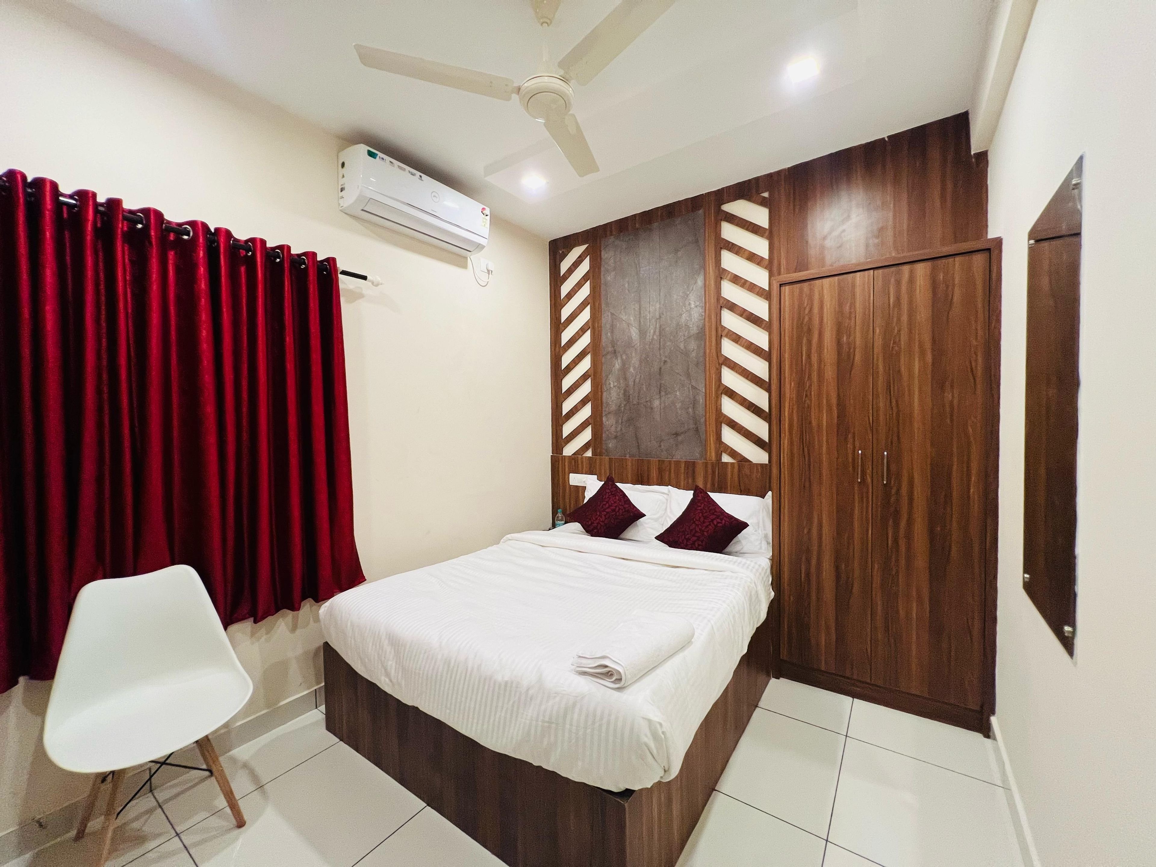 Habitación de hotel con cama, una silla, armario y aire acondicionado.