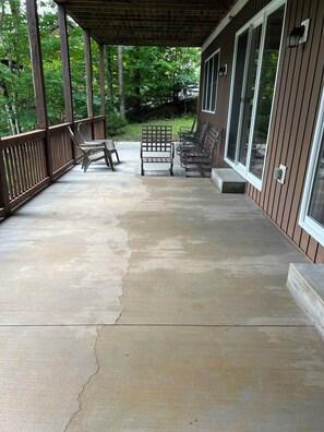A covered porch with a concrete floor, wooden railings, and a row of metal chairs. - 4Bdrm Lakefront on Quiet Cove. Gradual slope from road to water. (Jacksboro)