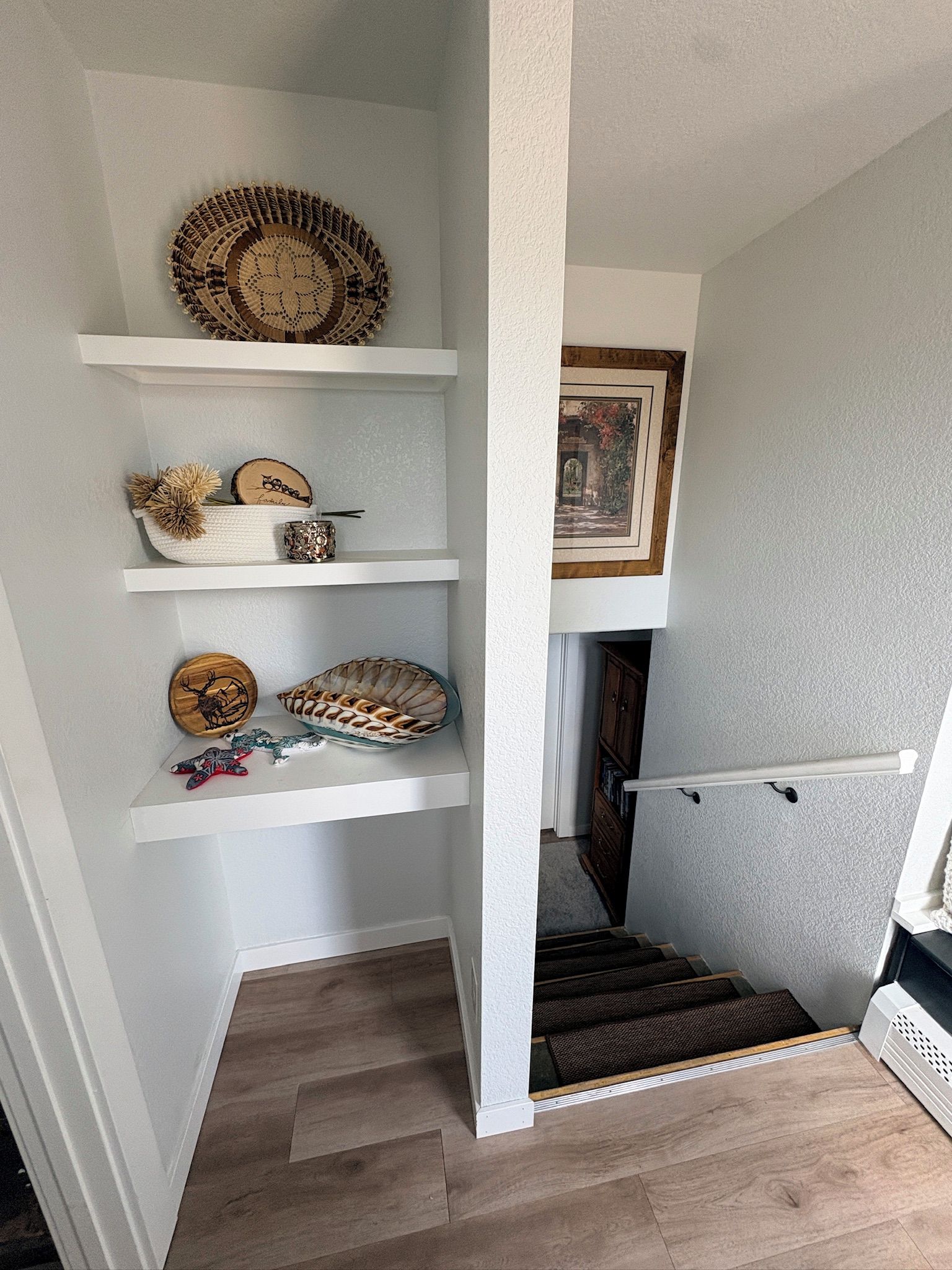 Una escalera con una pared blanca y un suelo de madera.