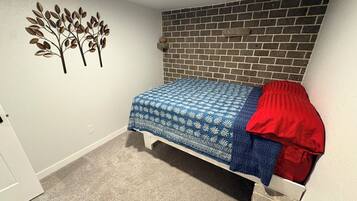 A bedroom with a bed, a brick wall, and a wall decoration.
