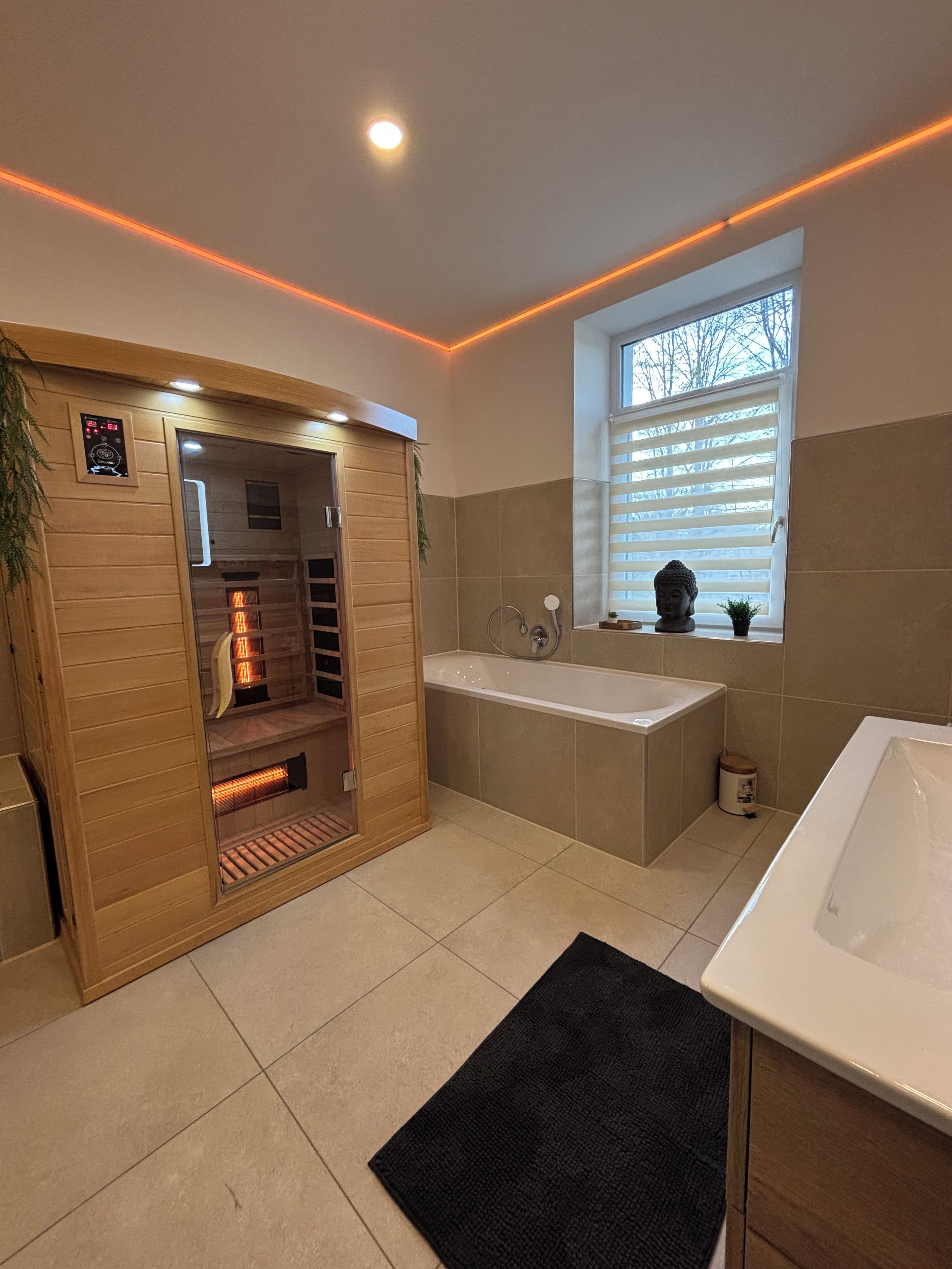 Ein modernes Badezimmer mit einer Holzauszeit, einer Badewanne und einem Fenster mit Jalousien.