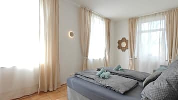 Une chambre d’hôtel avec deux lits, des rideaux beiges, un luminaire fixé au mur et un miroir hexagonal.