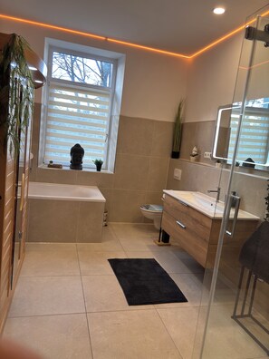 A modern bathroom with a bathtub, toilet, and sink.