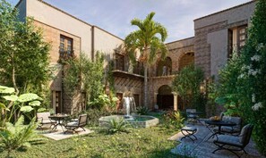 A courtyard with a fountain, outdoor seating, and lush greenery. - Aria Santa María (Santo Domingo)