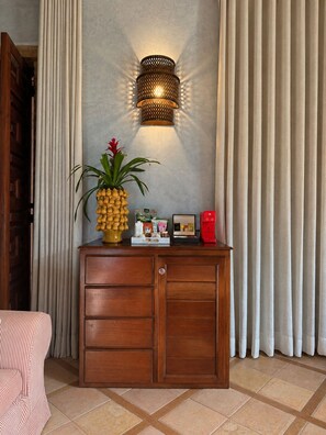 A wooden cabinet with drawers, a wall-mounted light fixture, and a potted plant with a red flower. - Aria Santa María (Santo Domingo)
