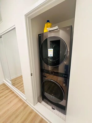 Eine moderne Küche mit integriertem Backofen und Mikrowelle, einem kleinen Fenster und einer Tür zu einem anderen Raum.