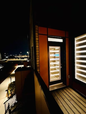 A nighttime view of a building's exterior with a lit entrance and a window with blinds. - Modern & Cozy Townhouse - 2 Bed + 3 Bath w/Parking (Brampton)
