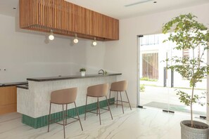 Een moderne keuken met een houten spilplafond, een marmeren aanrecht en drie barkrukken.