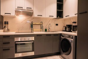 A modern kitchen with a built-in oven, a washing machine, and a coffee maker. - NOK Tropical 1BR Escape in Vistacana (Punta Cana)