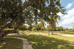 A park with a paved walkway, benches, and palm trees. - NOK Tropical 1BR Escape in Vistacana (Punta Cana)