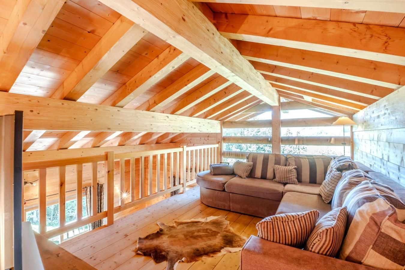 A wooden interior with a high ceiling, a sofa, and a fur rug.