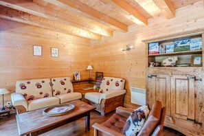A cozy log cabin interior with a sofa set, a coffee table, and a cabinet with books. - Chalet, 300m from ski slopes, terrace, tv, 124m², Le Grand Bornand (Le Grand-Bornand)