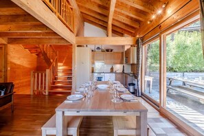 A wooden interior with a dining table set for a meal, a staircase, and large windows. - Chalet, 300m from ski slopes, terrace, tv, 124m², Le Grand Bornand (Le Grand-Bornand)
