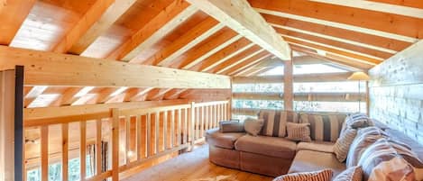 A wooden interior with a high ceiling, a sofa, and a fur rug.