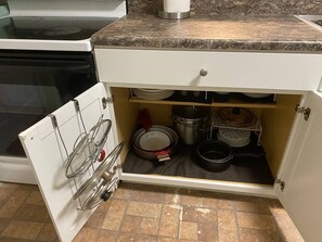 Une cuisine équipée d’un four encastré, d’un plan de travail et d’un meuble contenant de la vaisselle et des ustensiles de cuisine.