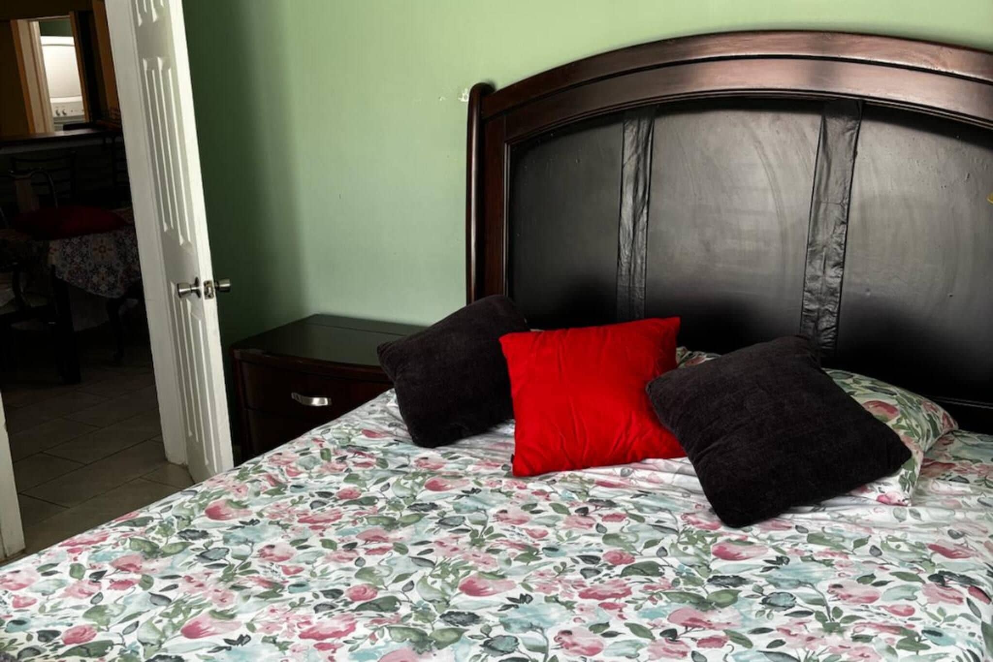 Una cama con colcha estampada, cabecera oscura y dos almohadas.