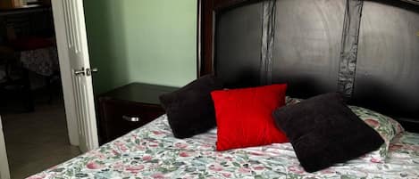 Una cama con colcha estampada, cabecera oscura y dos almohadas.