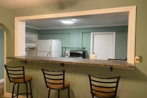 A kitchen with a bar area, three chairs, a refrigerator, a microwave, and a coffee maker. - Downtown Sarasota House 3br,2ba, Pet-friendly,6ppl (Sarasota)
