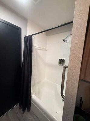 A bathroom with a bathtub, a shower, and a door.