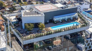 Un bâtiment moderne doté d’une piscine sur le toit, d’un espace extérieur aménagé et d’une façade en verre.