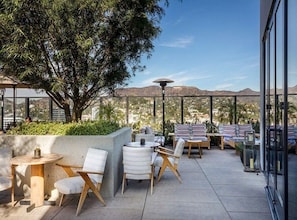 Un patio al aire libre con mobiliario, una mesa y vistas a las montañas.