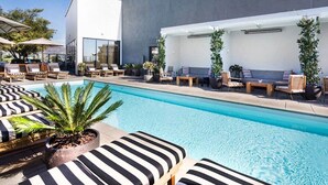 Un espace piscine moderne, doté de chaises longues et d’une grande piscine.
