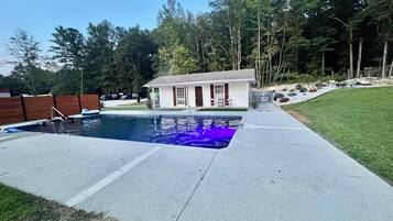 Una piscina comunitària amb una casa al fons.