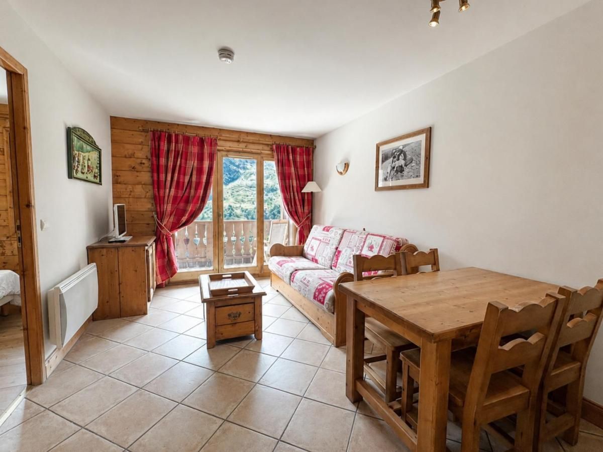 Una habitación acogedora con una mesa de comedor de madera, un sofá y una ventana con cortinas.