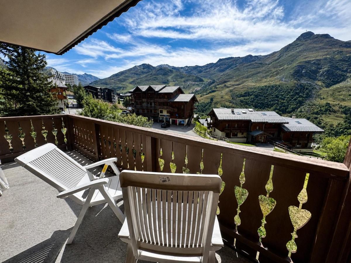 Un balcon avec vue sur les montagnes, une clôture en bois et une chaise.