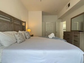 Ein Hotelzimmer mit einem großen Bett, einem Nachttisch mit Lampe, einem Schminktisch und einem Spiegel.