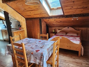 A cozy wooden room with a bed, a table with chairs, and a skylight. - 2nd floor, balcony, parking, tv, 24m², Valloire (Valloire)
