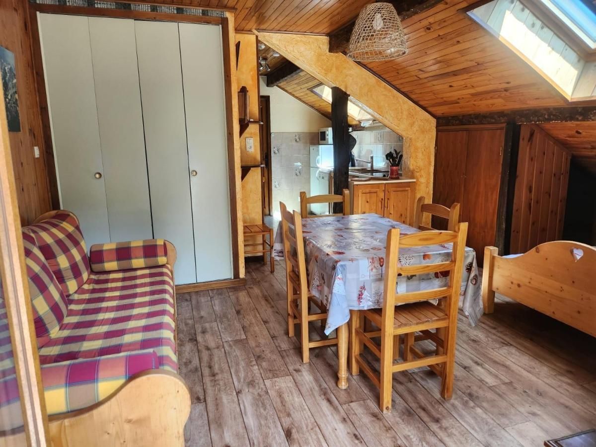 Een gezellige kamer met houten plafond, een eettafel met stoelen, een sofa en een keukenhoek met kastjes en een spoelbak.