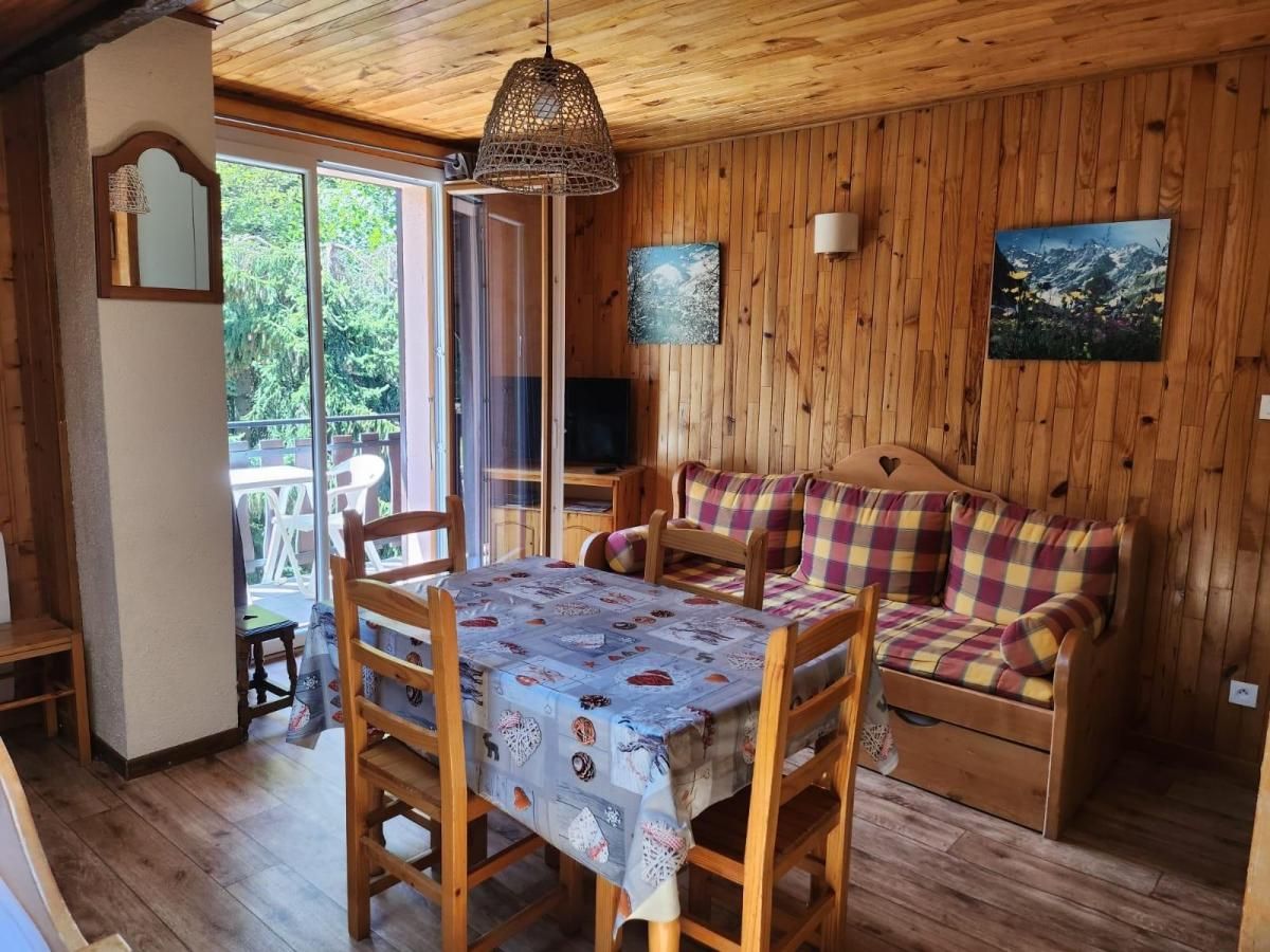 A wooden interior with a dining table, chairs, a sofa, and a large window.