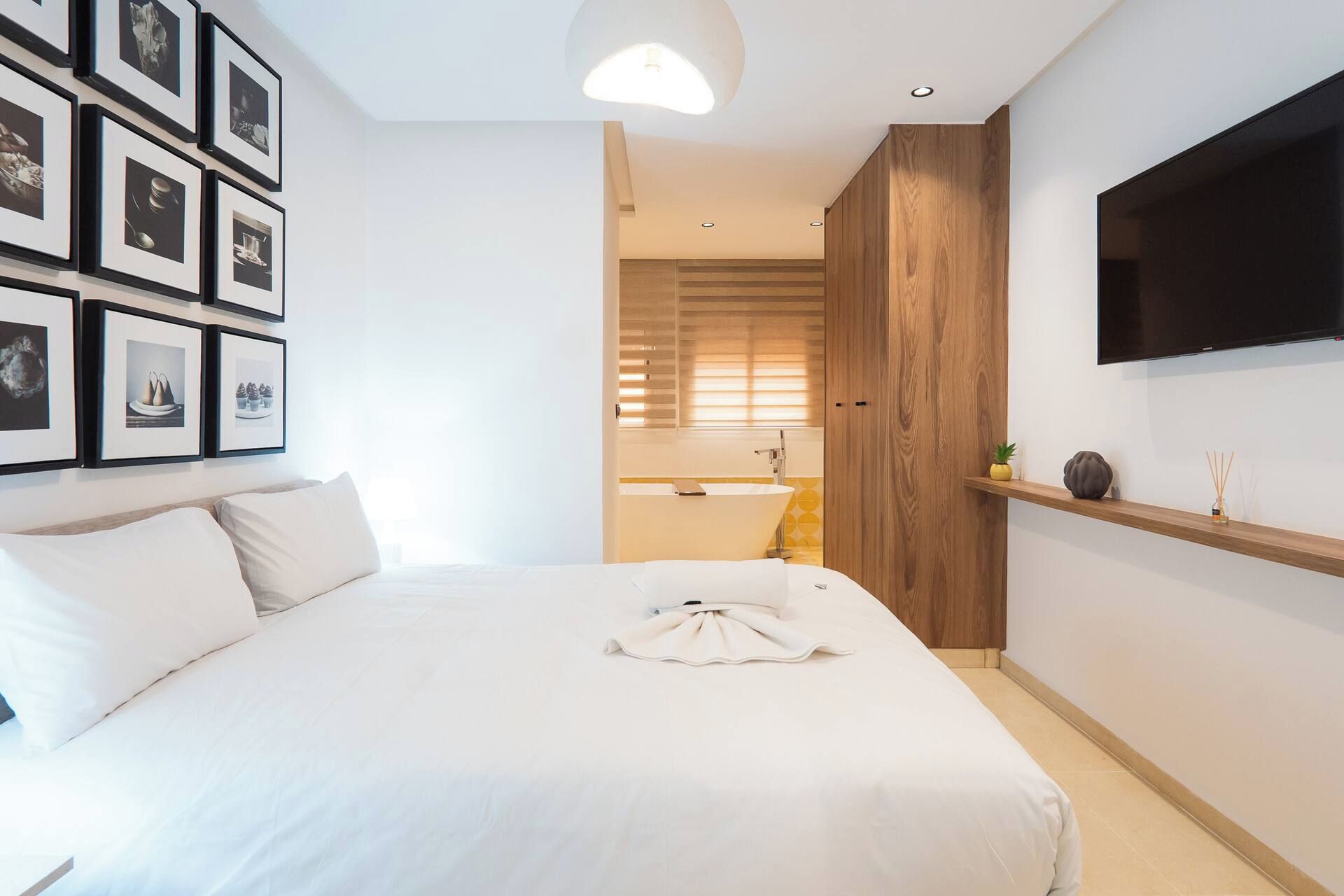 Une chambre d’hôtel avec un grand lit, un téléviseur fixé au mur et un mur orné de tableaux.