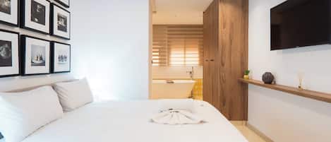 Une chambre d’hôtel avec un grand lit, un téléviseur fixé au mur et un mur orné de tableaux.