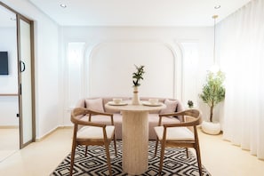 Ein moderner Essbereich mit einem runden Tisch, zwei Stühlen, einer Couch und einem Blumentopf.