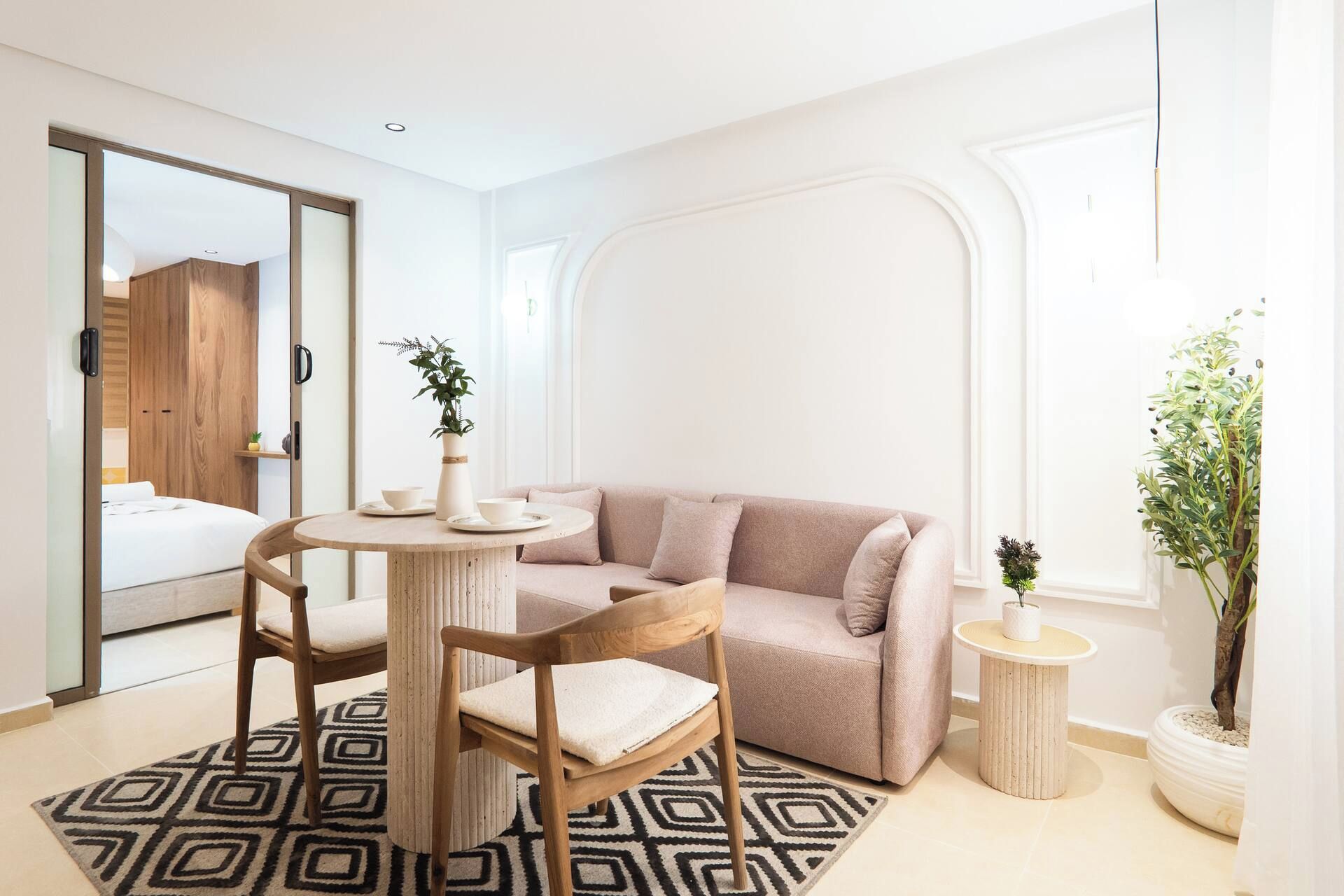 A modern living room with a round dining table, a beige sofa, and a small side table.