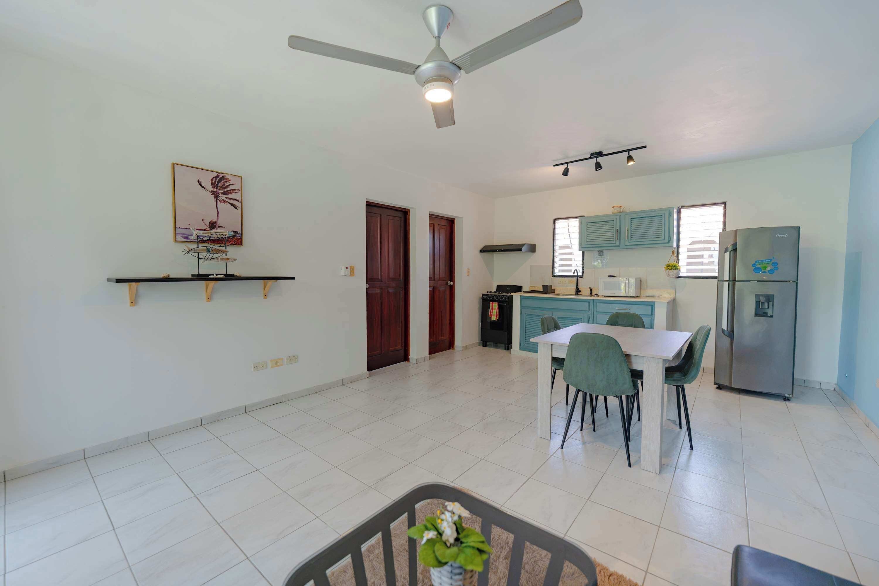A spacious kitchen with a dining area, a ceiling fan, and a refrigerator.